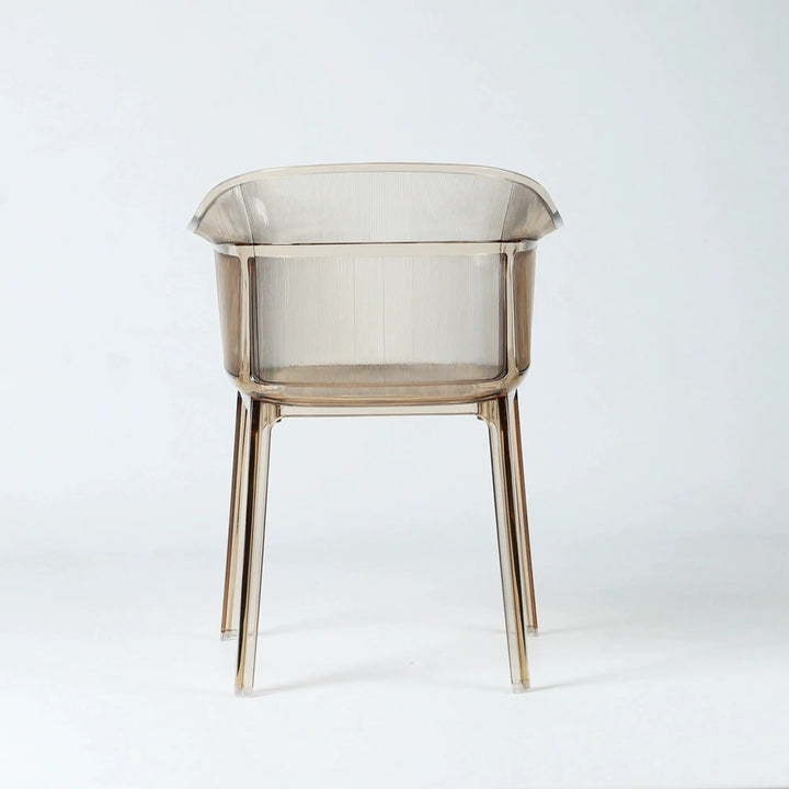 Translucent amber polycarbonate chair with sculptural wraparound silhouette and fine vertical detailing on back and seat.