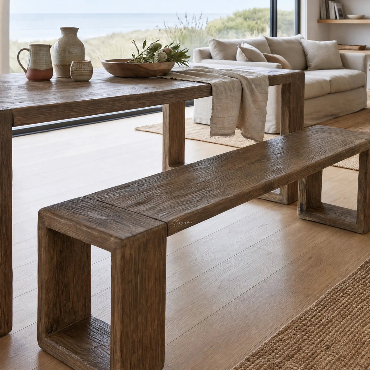 Reclaimed elm dining bench with 220cm length, raw surface texture, and substantial U-shaped supports in a sunlit room.