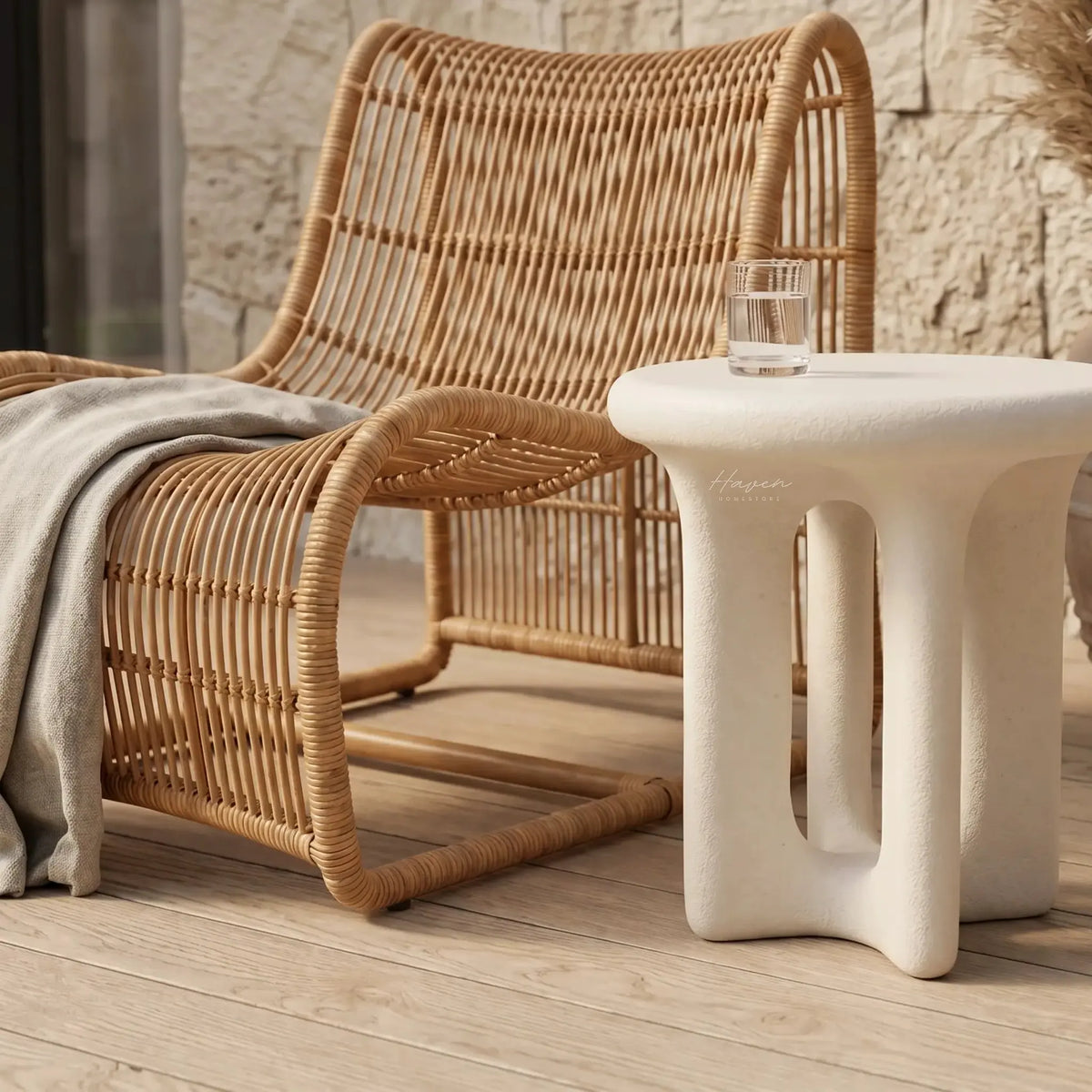 Yepa End Table with sculptural curves and linen-toned GRC, stone-like texture beside a wicker chair.