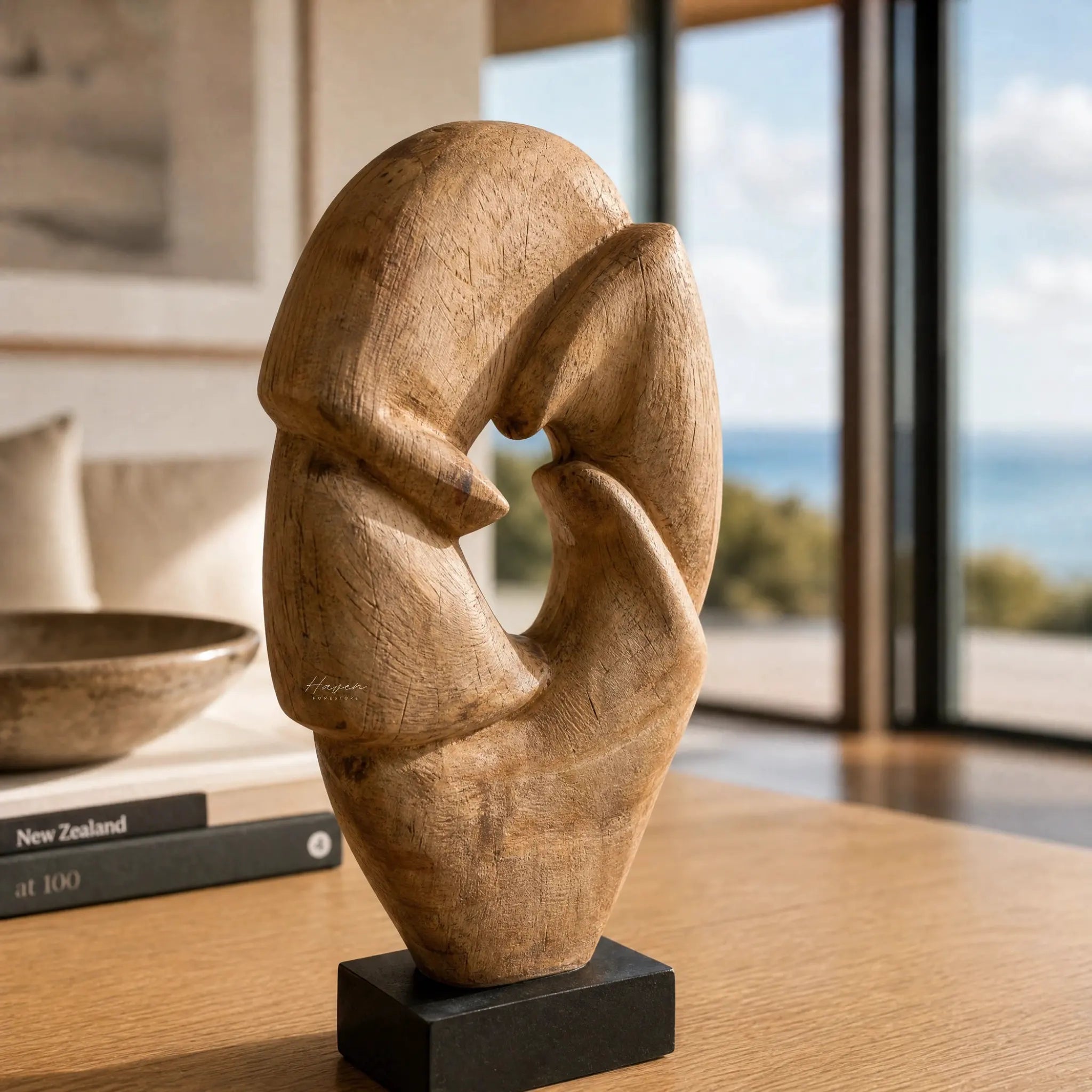 Loop Sculpture handcrafted from mango wood with a flowing organic form and warm texture on a black pedestal.