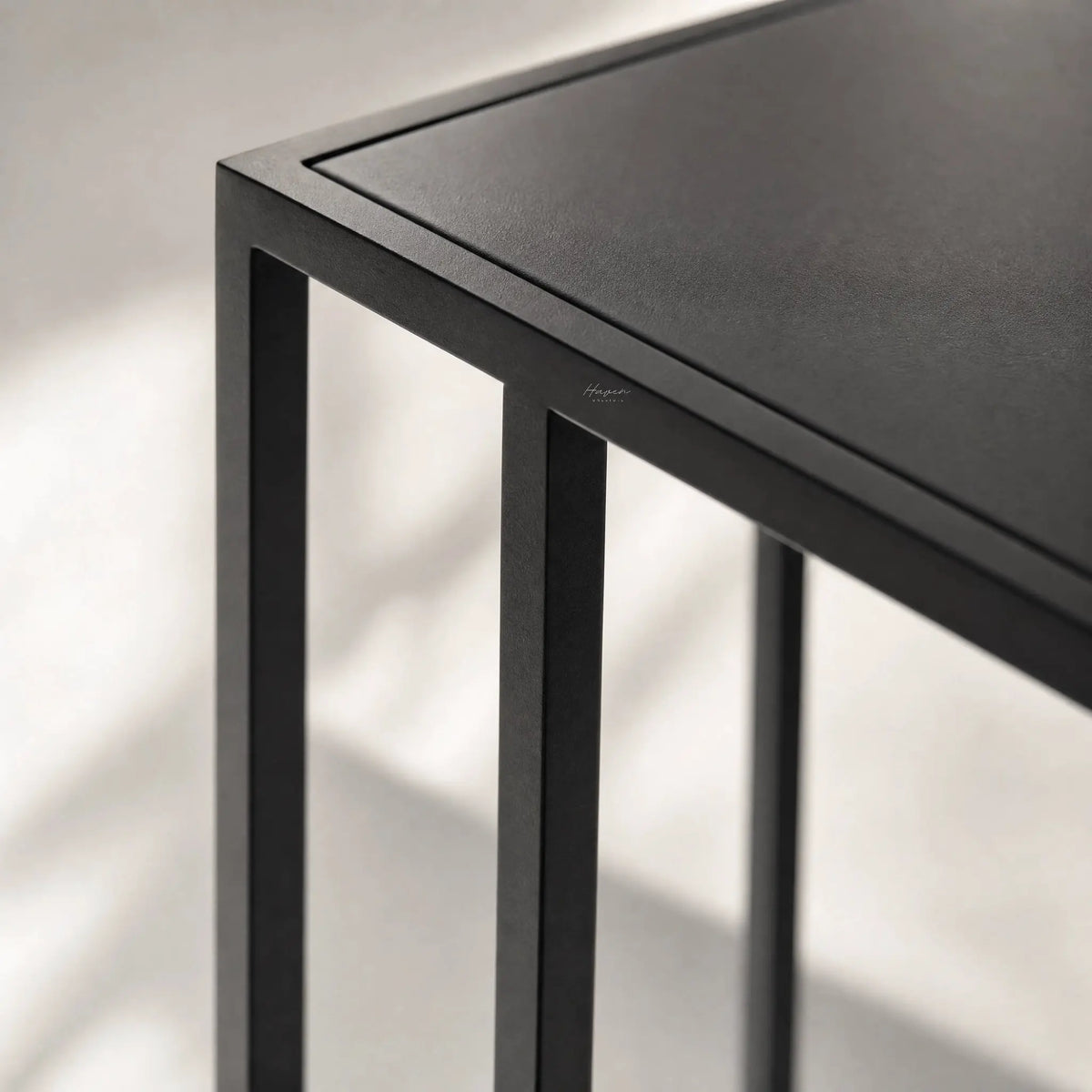 Cantilever Side Table - Min 2 in black iron with a clean cantilever design beside a sofa or bed.