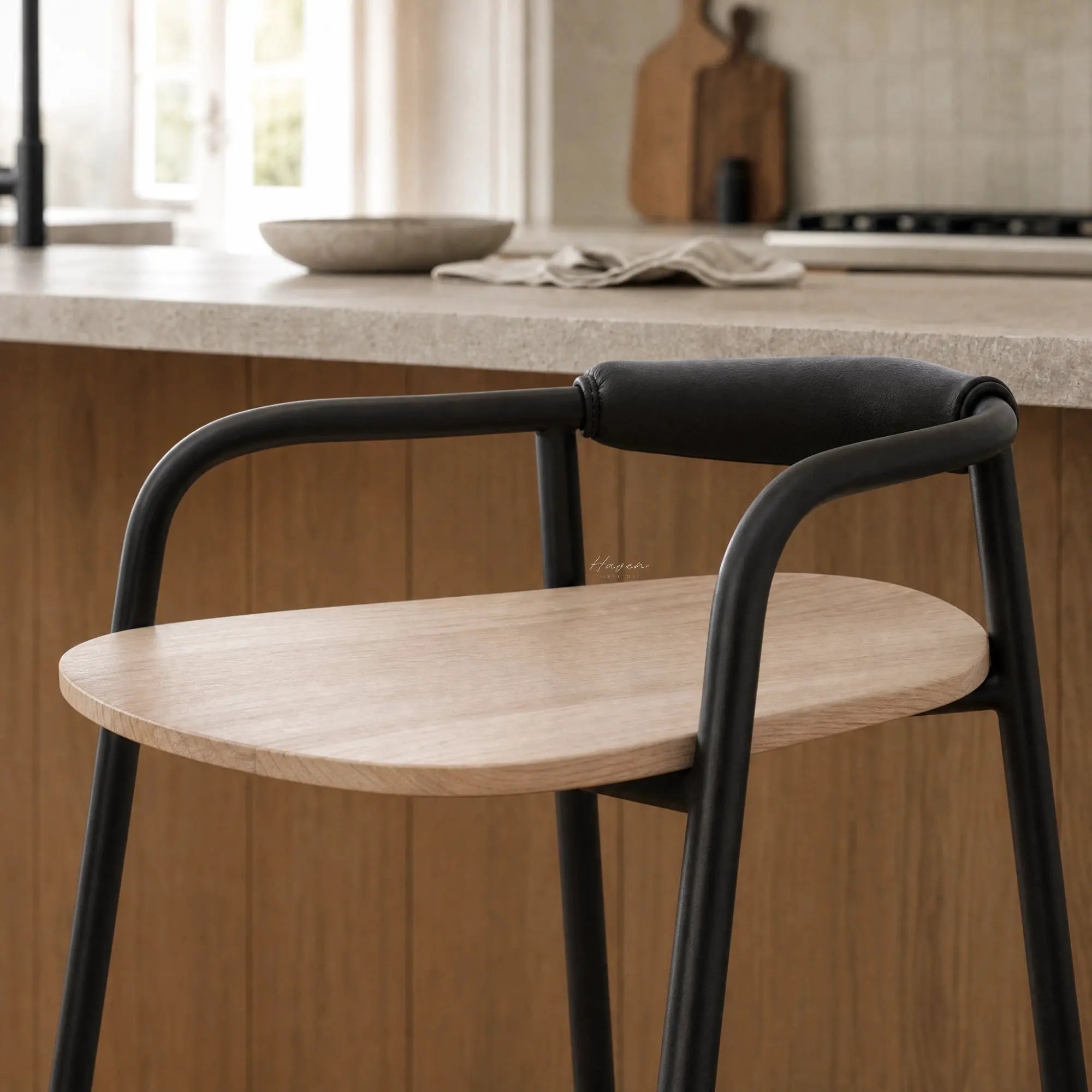 Scandinavian counter stool with natural ash wood seat and padded black leather backrest on a slim black metal frame.
