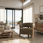 Olive lounge chair with curved back and exposed ash wood frame in a bright living room with ocean view.