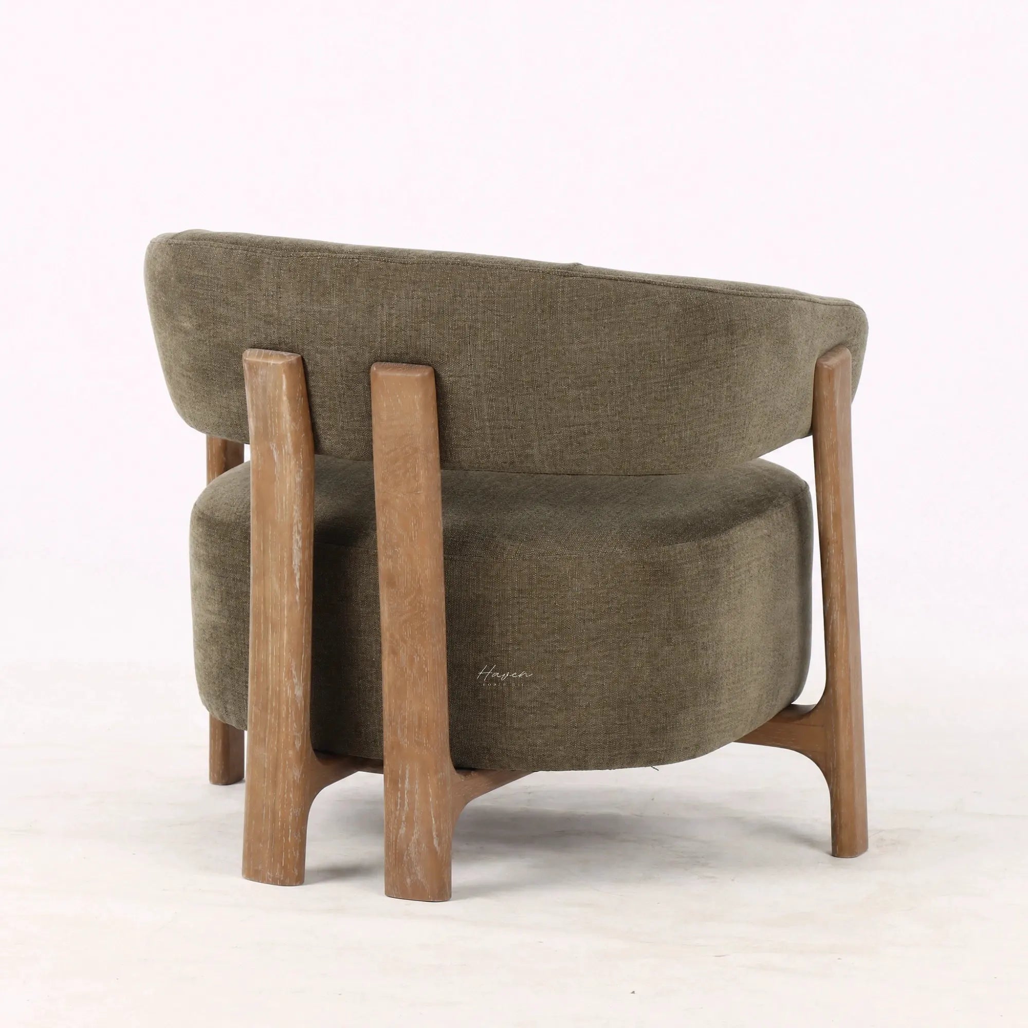 Back view of olive lounge chair with curved back, textured upholstery, and exposed ash wood frame.