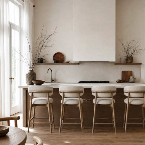 Four light ash counter stools with cream upholstery line a kitchen island, adding warmth and relaxed comfort to the space.