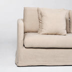 Beige slipcover sofa with soft tailored polyester fabric, generous cushioning, and a relaxed, inviting design featuring a matching throw pillow.