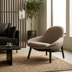 Pierre Chair - Latte in a modern living room with a dark sofa, wooden slat divider, and a potted plant.