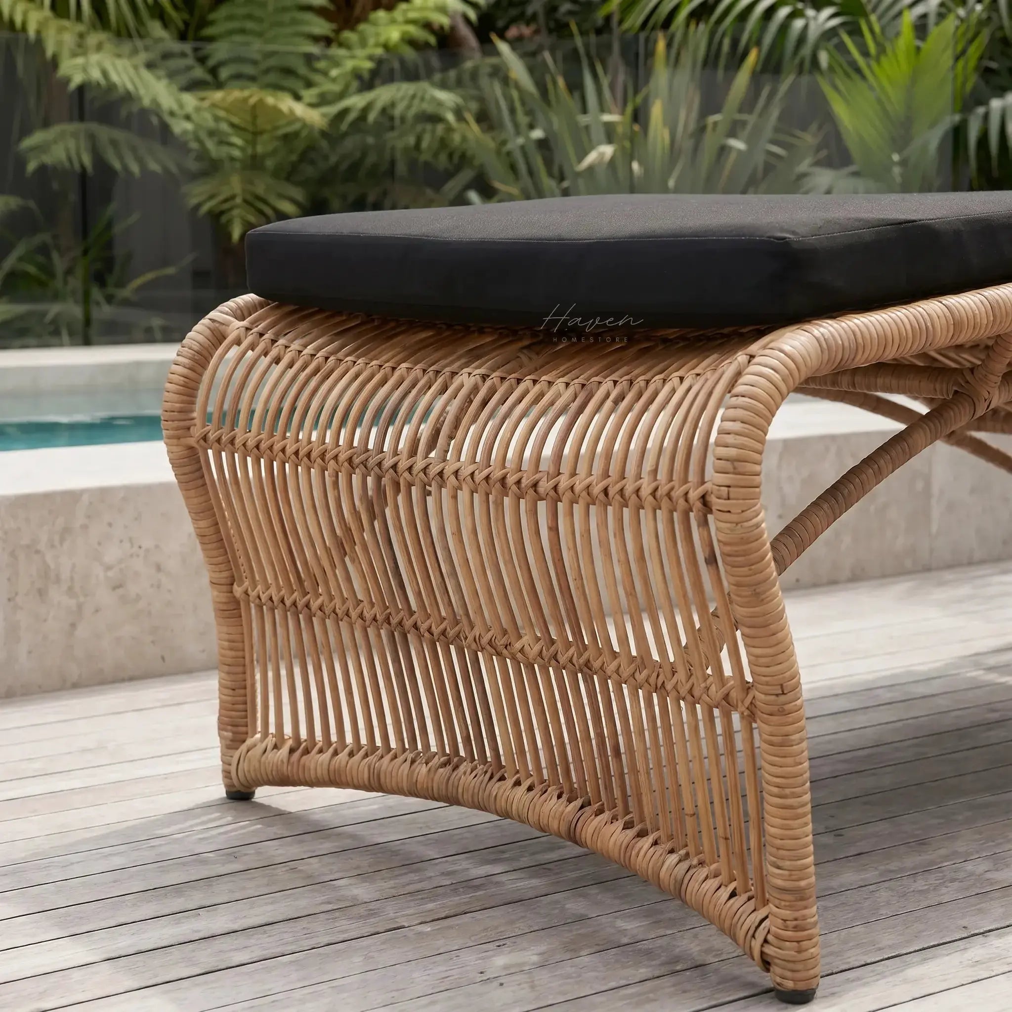 Wave Sun Lounger with black cushion on a woven rattan-style frame, outdoor deck setting.