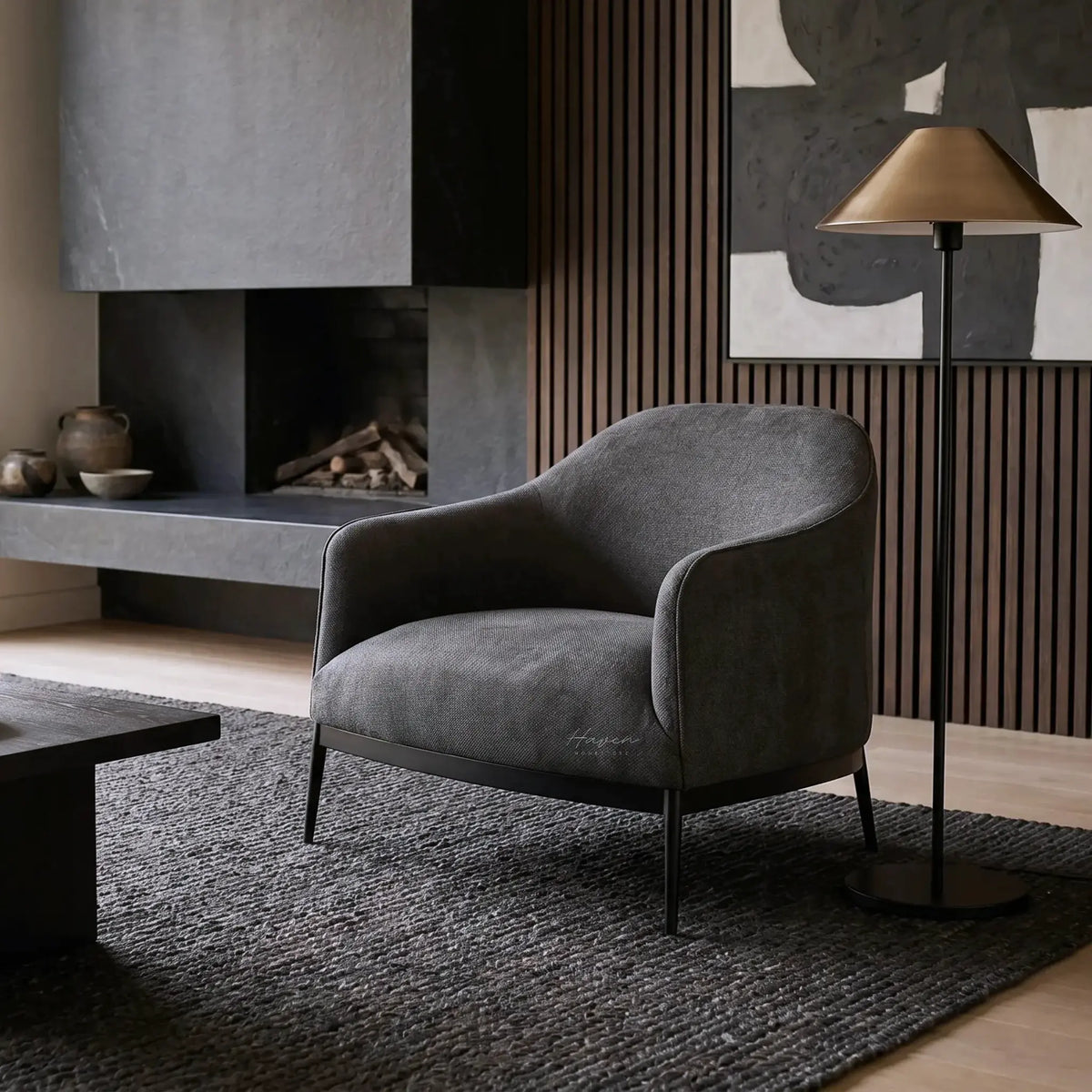 The Sydney Chair in dark gray recycled-polyester upholstery, modern NZ living room with lamp and wood paneling.