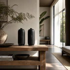 Black hand-thrown terracotta vase set/2 displayed on rustic wooden table in minimalist living space.