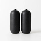 A minimalist black vase set, crafted from terracotta with a sleek, smooth finish. Hand-thrown by artisan potters for a modern home aesthetic.