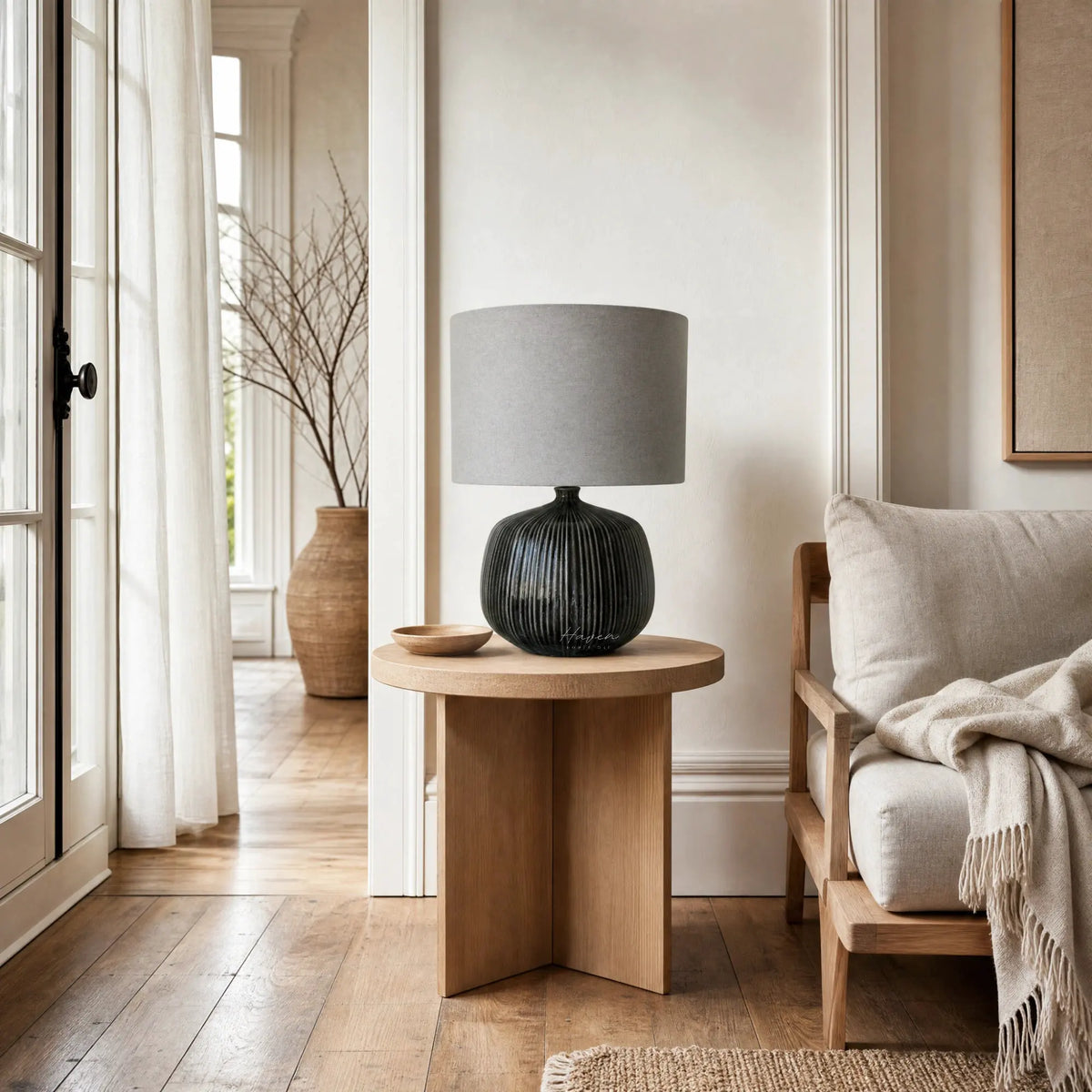 Aksel Table Lamp in Slate with ribbed ceramic base and linen shade sits on wood side table in bright living room.